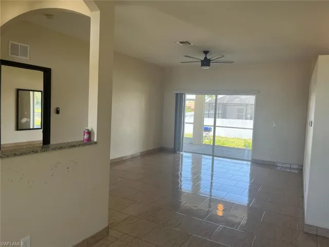 Empty room with a ceiling fan, baseboards, arched walkways, and a smoke detector
