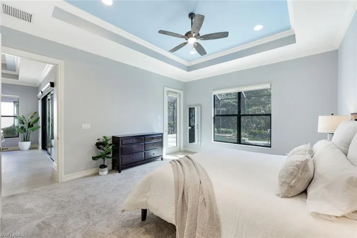 Bedroom with a tray ceiling, crown molding, ceiling fan, new carpeting and access to lanai