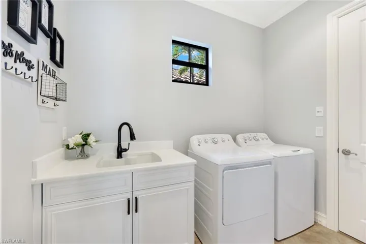 Washroom featuring white cabinets, quartz counters, washer and dryer, crown molding, and sink
