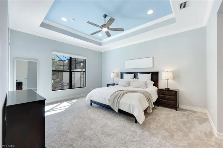 Bedroom with a tray ceiling, crown molding, ceiling fan, new carpeting and access to lanai