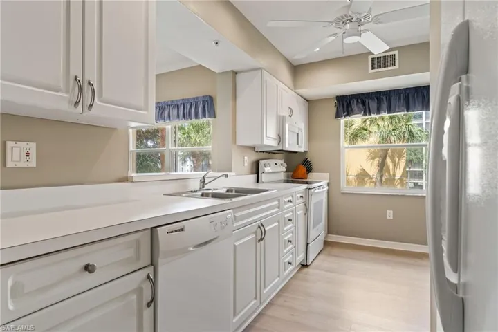 Kitchen featuring white appliances, white cabinetry, light countertops, ceiling fan, and light wood-type flooring