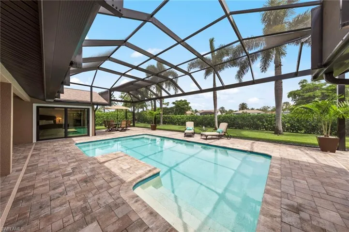 Outdoor pool with a sunroom, a patio area, glass enclosure, and a yard