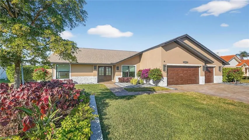 View of front of home with stone siding, stucco siding, a front lawn, driveway, and a garage