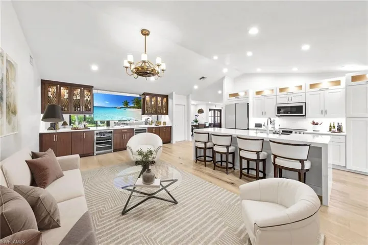 Living area with wine cooler, vaulted ceiling, a chandelier, light wood-style floors, and recessed lighting