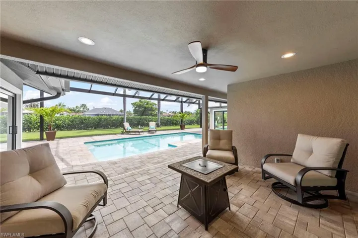 Outdoor pool featuring a sunroom, glass enclosure, a patio area, a ceiling fan, and a yard
