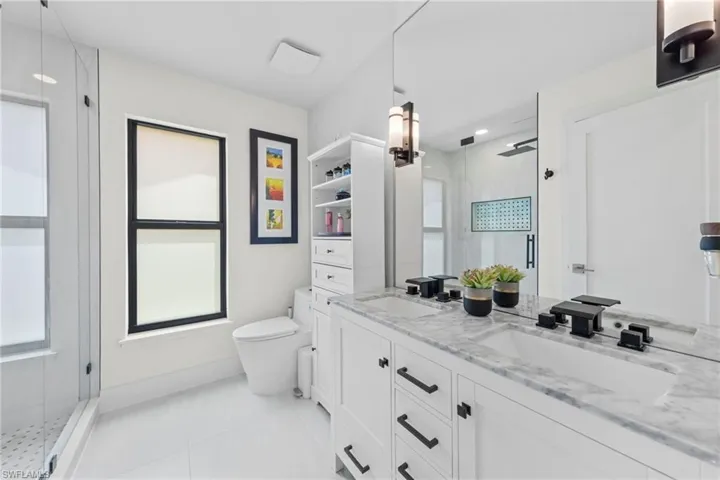 Full bathroom featuring double vanity, a stall shower, and light tile patterned flooring