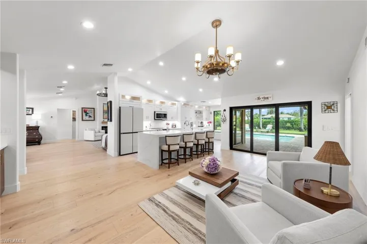 Living room with lofted ceiling, light wood-style flooring, a chandelier, and recessed lighting