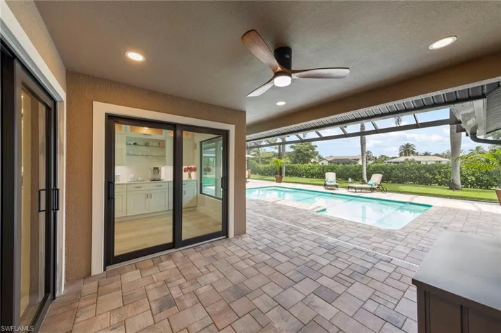 Outdoor pool with a patio area, a sunroom, and a ceiling fan