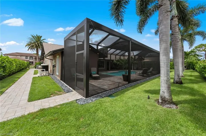 Rear view of house featuring a sunroom, a lanai, a yard, an outdoor pool, and a patio