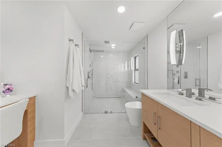 Bathroom featuring vanity, a shower stall, light tile patterned floors, and recessed lighting
