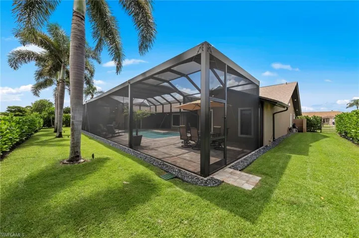 Rear view of house featuring a sunroom, a yard, glass enclosure, and an outdoor pool
