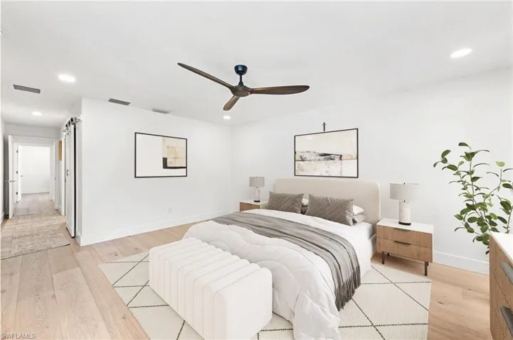 Bedroom featuring recessed lighting, light wood-style flooring, a ceiling fan, and a barn door