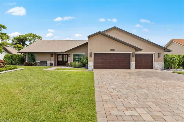 Ranch-style house with stone siding, stucco siding, and decorative driveway