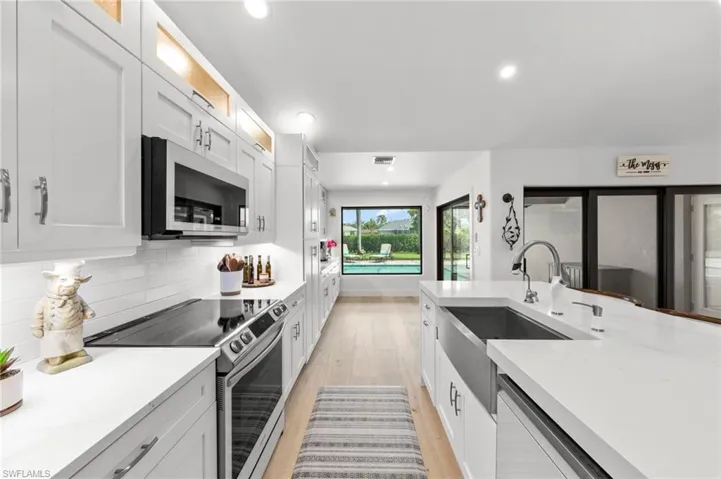 Kitchen with appliances with stainless steel finishes, light stone countertops, recessed lighting, and white cabinets
