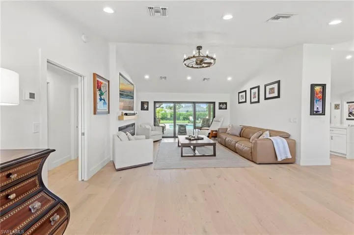 Living room with vaulted ceiling, recessed lighting, light wood-style floors, and a chandelier
