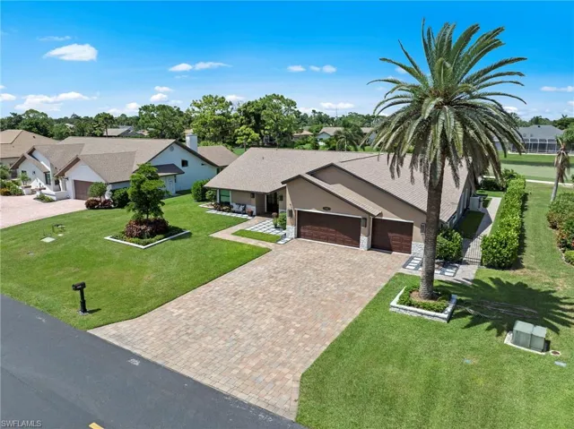 Mid-century home featuring a residential view, decorative driveway, an attached garage, roof with shingles, and a front lawn