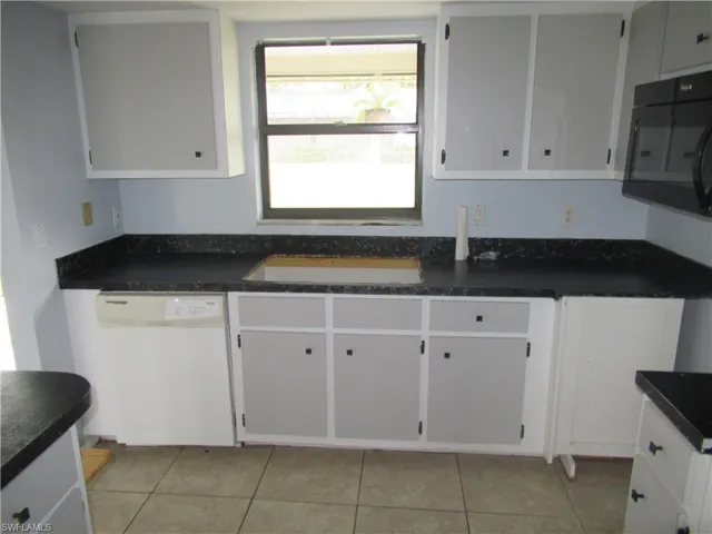 Kitchen with white dishwasher, white cabinetry, and light tile patterned floors