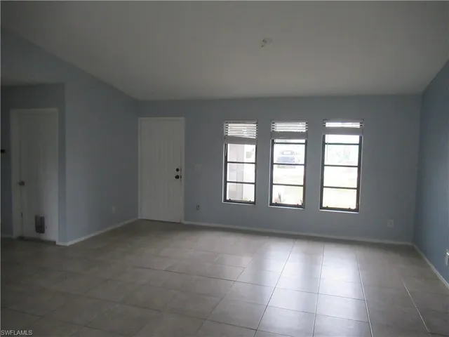 Unfurnished room with vaulted ceiling and light tile patterned flooring