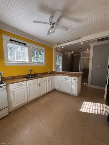 Kitchen featuring white cabinets, a peninsula, ornamental molding, dark countertops, and range