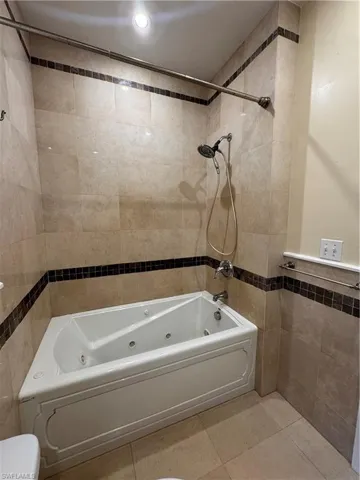 Bathroom featuring tile walls, a combined bath / shower with jetted tub, tile patterned flooring, and recessed lighting