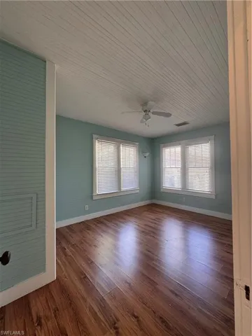 Spare room with dark wood-style flooring, wood ceiling, and ceiling fan