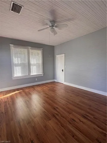 Unfurnished room featuring dark wood-style flooring, wooden ceiling, and ceiling fan