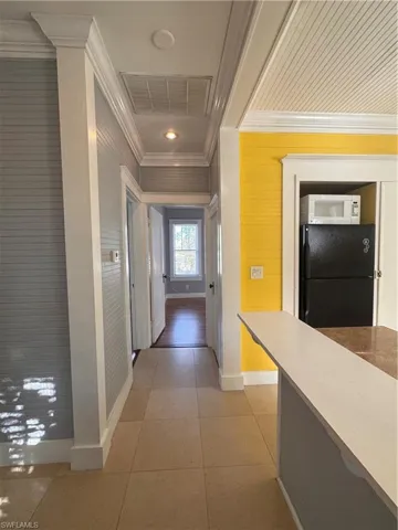 Hall with crown molding and light tile patterned flooring