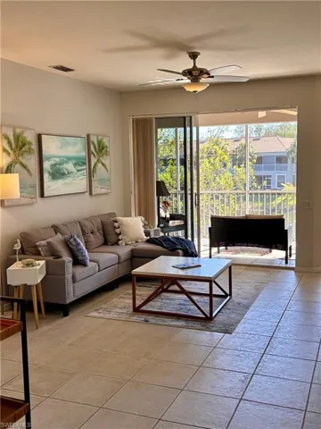 Living room with tile flooring leads has a triple slider that leads out to the screened lanai.