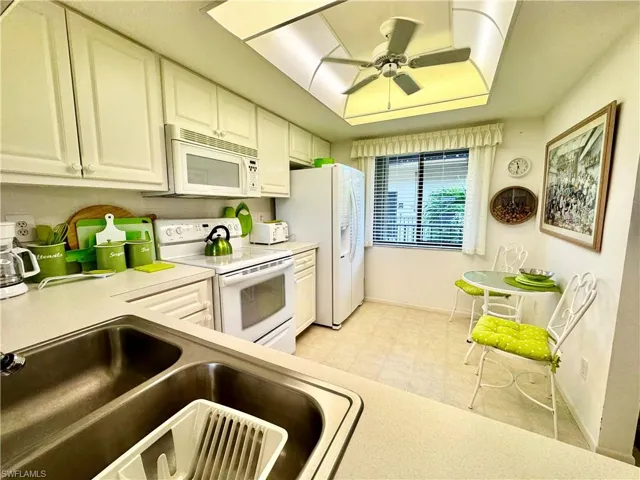 Kitchen featuring white appliances, ceiling fan, and sink