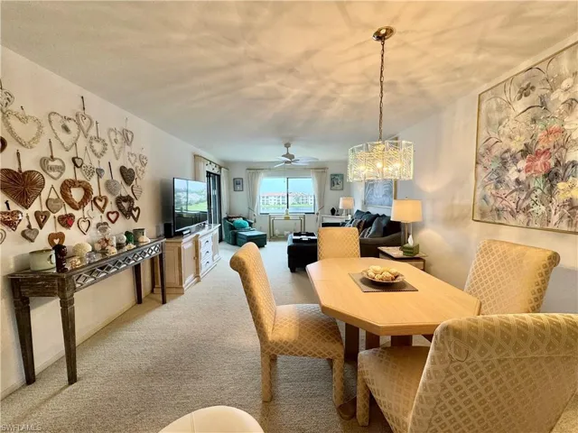 Dining area featuring light colored carpet and ceiling fan with notable chandelier