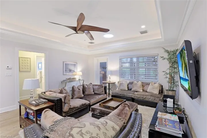 Living area featuring a tray ceiling, ceiling fan, light wood-style flooring, recessed lighting, and ornamental molding
