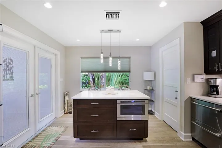 Kitchen with stainless steel appliances, light wood-type flooring, light countertops, dark brown cabinetry, and recessed lighting