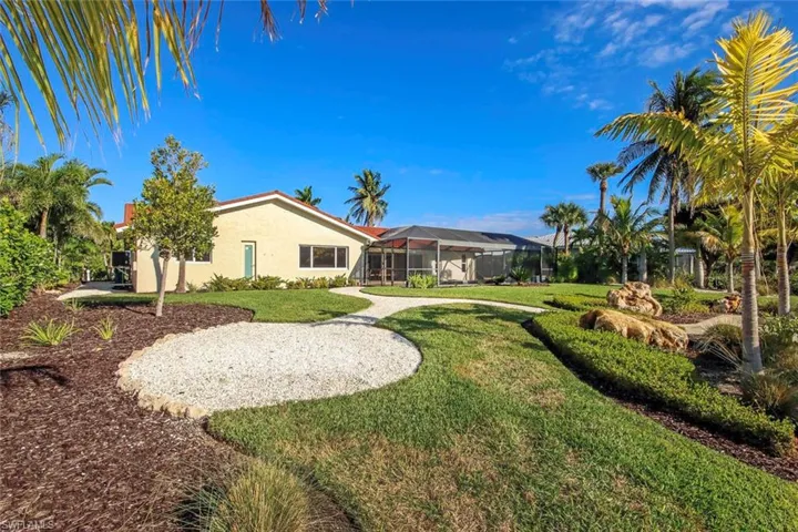 Rear view of house with a sunroom, stucco siding, a yard, and glass enclosure