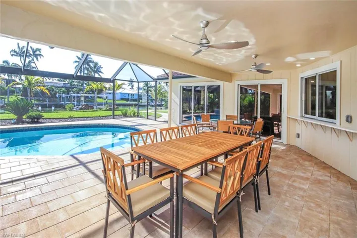 Outdoor pool featuring a patio, outdoor dining space, a sunroom, and a lanai