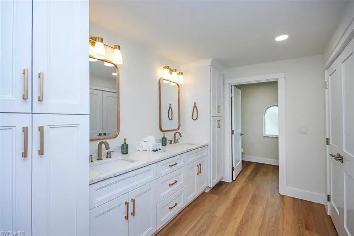 Full bathroom with double vanity, light wood-type flooring, and recessed lighting