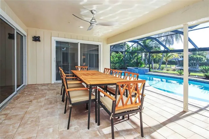Swimming pool featuring a patio, a sunroom, outdoor dining area, and glass enclosure