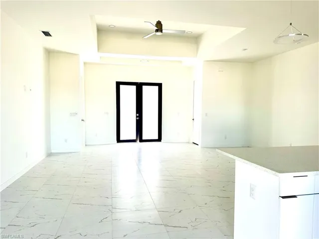 Empty room with baseboards, visible vents, a ceiling fan, marble finish floor, and french doors
