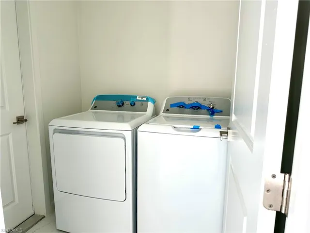 Laundry room featuring laundry area, washer and clothes dryer, and marble finish floor