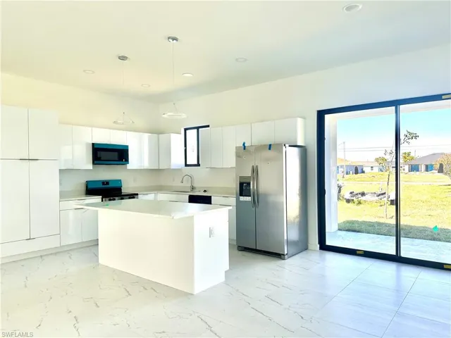 Kitchen with a center island, marble finish floor, appliances with stainless steel finishes, white cabinets, and a sink