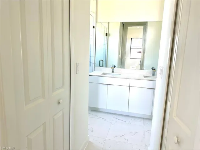 Bathroom with double vanity, marble finish floor, a sink, and a stall shower