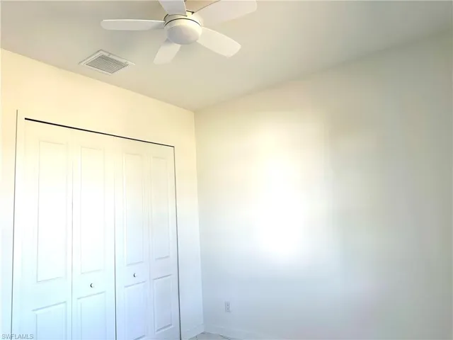 Unfurnished bedroom featuring a closet, visible vents, and a ceiling fan