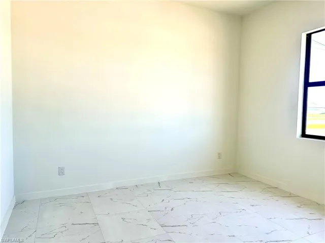 Unfurnished room featuring marble finish floor and baseboards