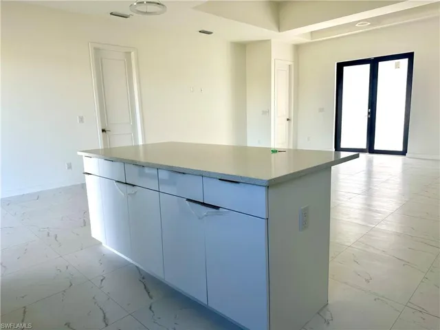 Kitchen featuring baseboards, marble finish floor, french doors, a center island, and modern cabinets