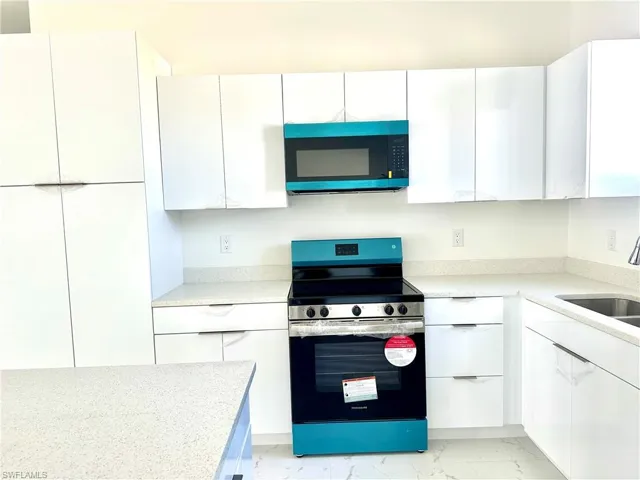 Kitchen with a sink, white cabinets, marble finish floor, electric stove, and modern cabinets