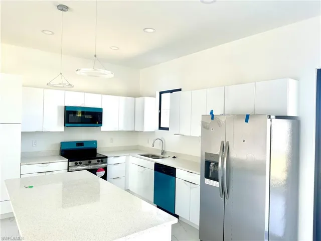 Kitchen with stainless steel appliances, white cabinetry, a sink, and a kitchen island