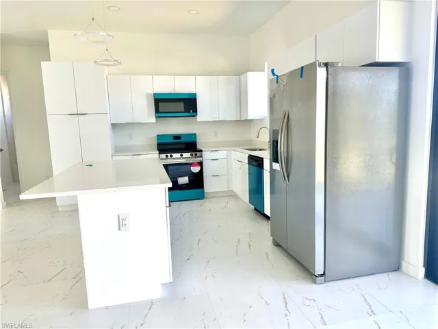 Kitchen featuring marble finish floor, decorative light fixtures, light countertops, appliances with stainless steel finishes, and white cabinets