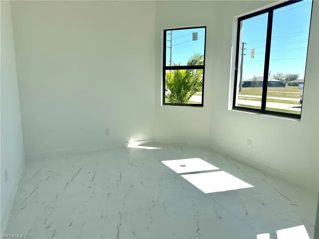 Empty room with marble finish floor, baseboards, and a wealth of natural light