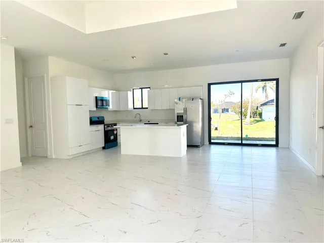 Kitchen featuring stainless steel appliances, modern cabinets, a kitchen island, and white cabinets