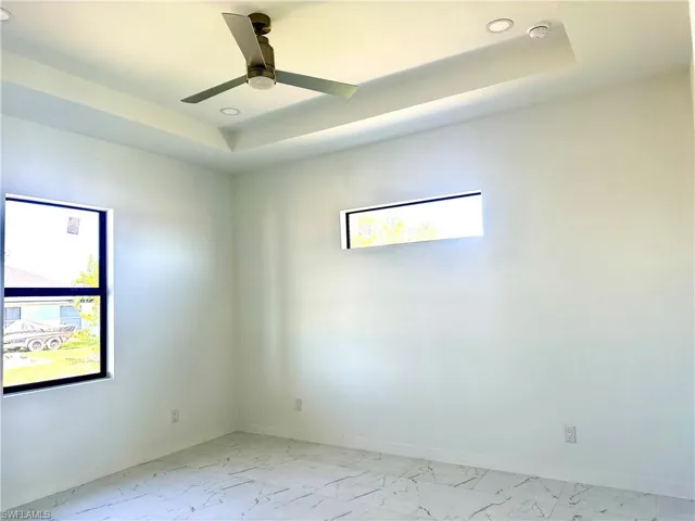 Unfurnished room featuring a tray ceiling, plenty of natural light, and baseboards