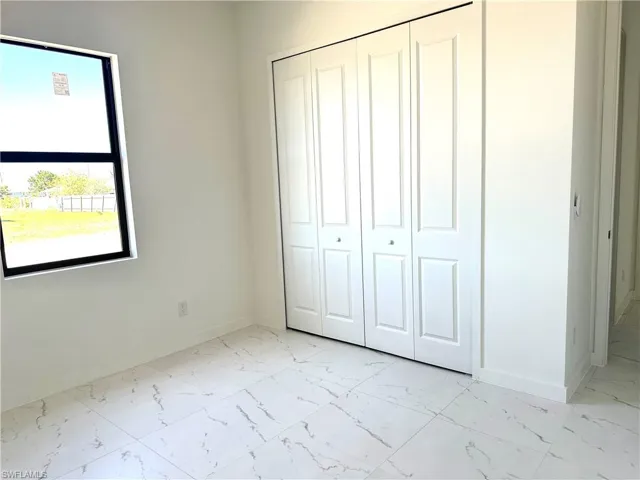 Unfurnished bedroom featuring a closet, marble finish floor, and baseboards